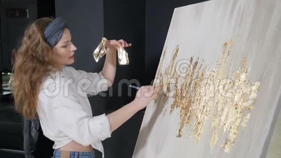 年轻的女艺术家将金叶应用于她的艺术品艺术家用一小片金色装饰图片艺术学校视频的预览图