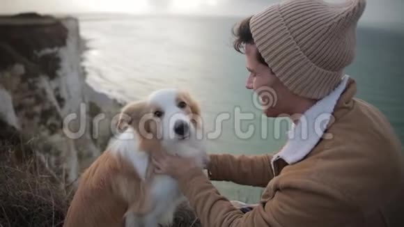诺曼底一个年轻的嬉皮士抚摸着一只边境牧羊犬一个旅行者坐在海边视频的预览图