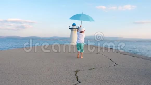 56岁的快乐男孩手里拿着雨伞在码头上走来走去快乐的男孩在码头上笑视频的预览图