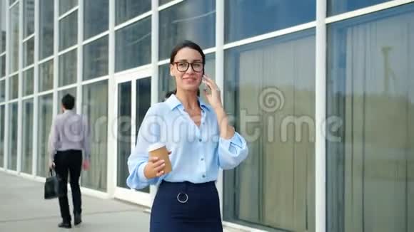 一位在商业区步行的独立女性在用手机说话微笑着视频的预览图