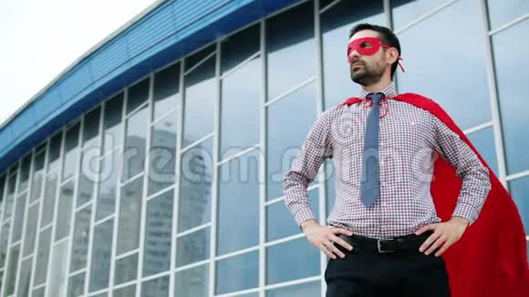 野心勃勃的男人戴着红色超级英雄面具和披风站在户外的肖像视频的预览图