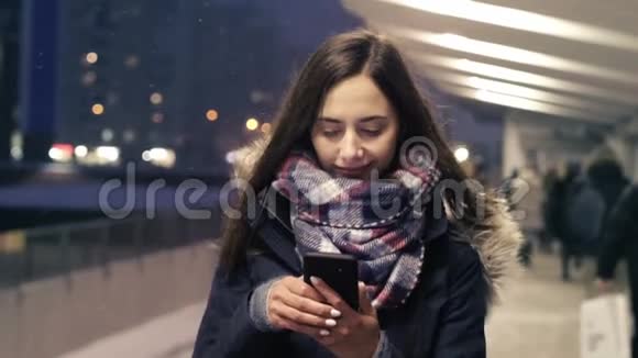 年轻的女人在地铁站走的时候使用智能手机视频的预览图