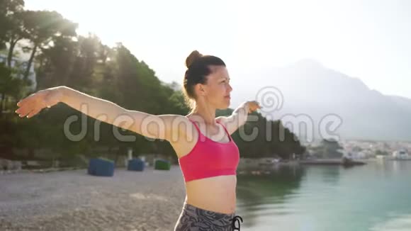 穿着运动服在海边练习瑜伽的可爱成年女人视频的预览图