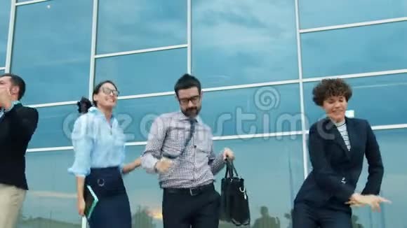 快乐的同事在城市街道的户外跳舞然后一个接一个地离开工作视频的预览图