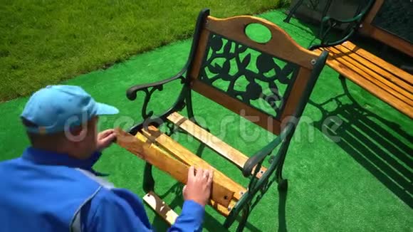 穿蓝色工作服的木匠在院子里加入木制复古长凳视频的预览图