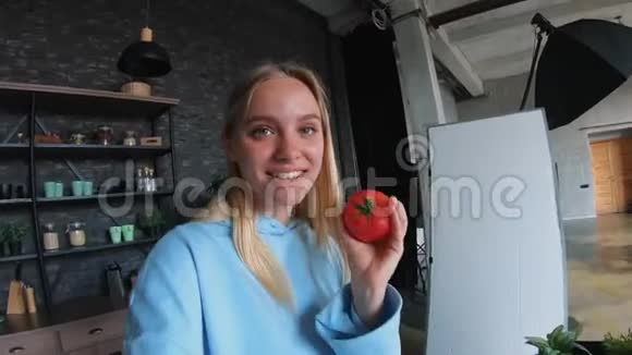年轻漂亮的金发女郎在厨房做饭时拍视频视频的预览图