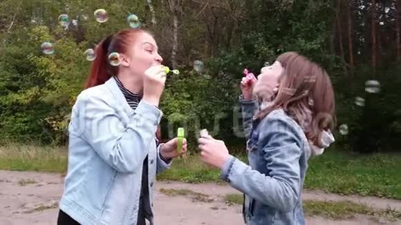 一个年轻的女人和她的女儿在一个夏天的晚上在公园里吹泡泡妈妈天家庭关系视频的预览图