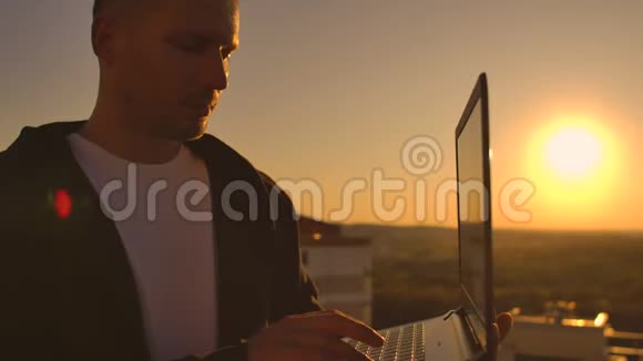 特写程序员在日落时分用手在笔记本电脑键盘上打字俯瞰屋顶一个商人在远程工作视频的预览图