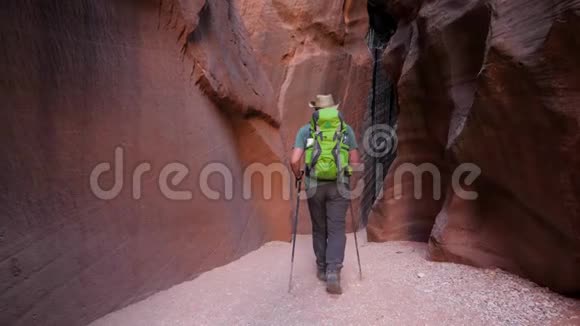 徒步旅行者在干涸的河床上在深槽峡谷的洞穴中带橙色曲线岩视频的预览图