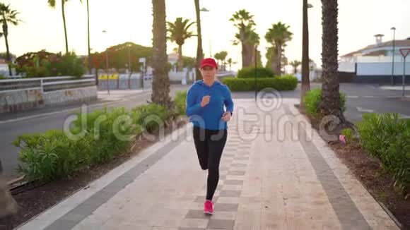 日落时女人沿着棕榈大道沿着街道跑健康的积极生活方式录像以不同的速度拍摄视频的预览图