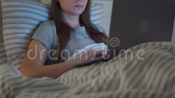 戴眼镜的女人晚上躺在床上用笔记本电脑工作她揉眼睛因为她又累又困视频的预览图