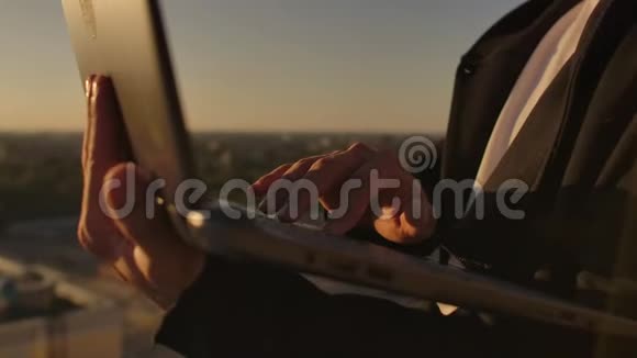 特写程序员在日落时分用手在笔记本电脑键盘上打字俯瞰屋顶一个商人在远程工作视频的预览图