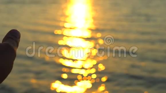 人手在海上日落海洋海滩一个人在大自然的背景海水上太阳和射线黄昏的光辉视频的预览图