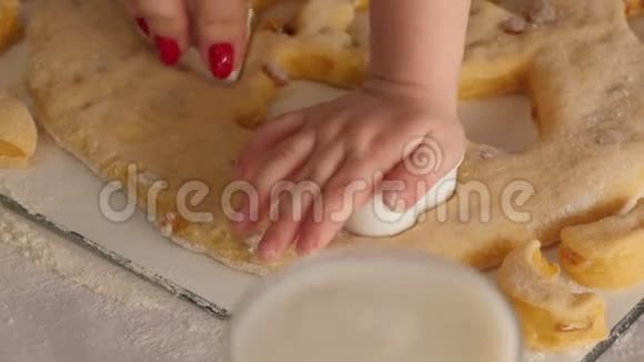 妈妈和女儿的特写从厨房的面团里切出饼干的形状视频的预览图