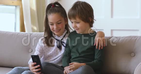 两个男孩在沙发上一起学习使用智能手机视频的预览图