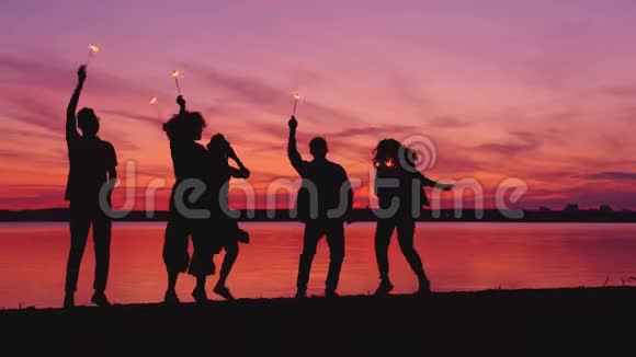 一群朋友在湖边的户外跳舞晚上有孟加拉灯玩得很开心视频的预览图