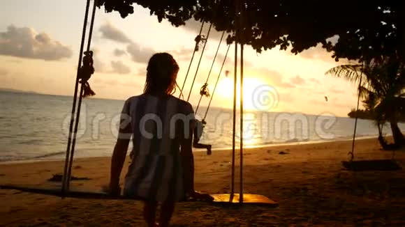 母亲和女儿在阳光明媚的夕阳下在海边骑着秋千视频的预览图