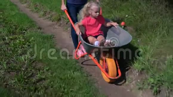 快乐的母亲开着手推车而她的学龄前女儿坐在手推车里视频的预览图