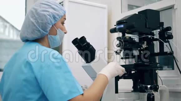女专家医学实验室工作人员正在显微镜下观察物质视频的预览图