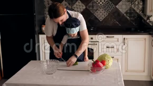 一位年轻的母亲教她的小女儿在厨房里切黄瓜视频的预览图