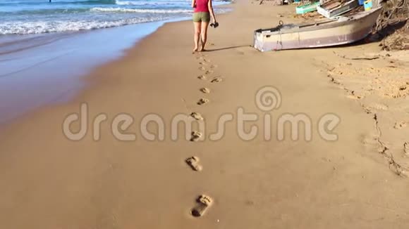 沙滩上留下脚印的年轻女子视频的预览图