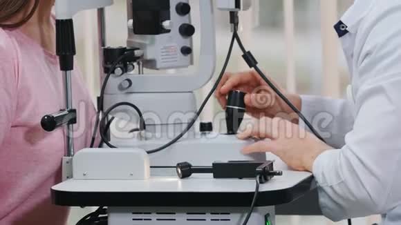 眼科治疗一位医生在一个宽敞的橱柜里用一台特殊的机器检查年轻女性视力视频的预览图