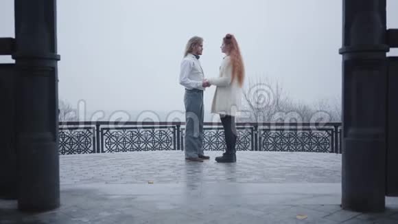 一个穿着复古风格衬衫和背心的时髦男人的长镜头单膝跪下向他的女朋友求婚青年视频的预览图