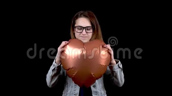 一个愤怒的年轻女人撕了一个心形的气球黑色背景上的愤怒女人情人节是视频的预览图