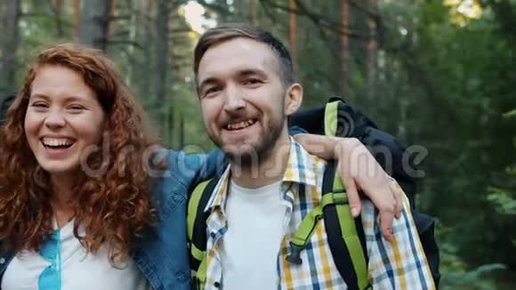 在树林里嬉笑的女孩和男人拥抱看镜头的肖像视频的预览图