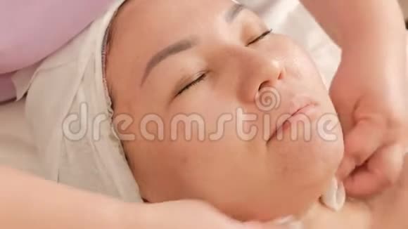 美容师的特写她用棉垫擦拭一张女脸一个在清洗过程中出现的亚裔女孩视频的预览图