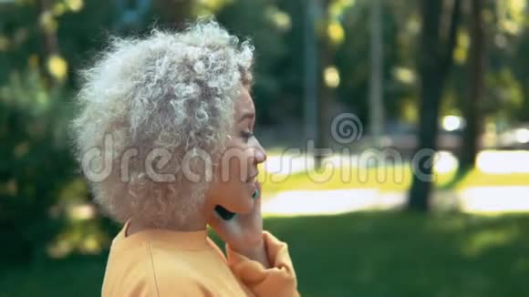 卷毛的女人打电话在户外散步视频的预览图
