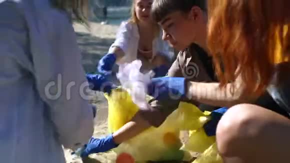 一群积极分子朋友在海滩上收集塑料垃圾近景视频的预览图