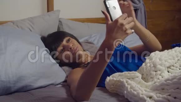 可爱的女人在床上自拍在黄昏的电话视频的预览图