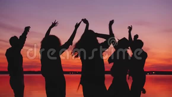 欢乐的学生在日落时在海滩上跳舞一起在户外聚会上放松视频的预览图