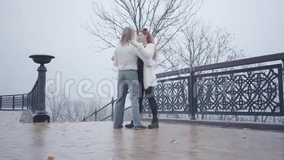 年轻的复古风格白种人夫妇在灰色天空的背景下在桥上跳舞穿着时髦白衬衫的年轻人视频的预览图