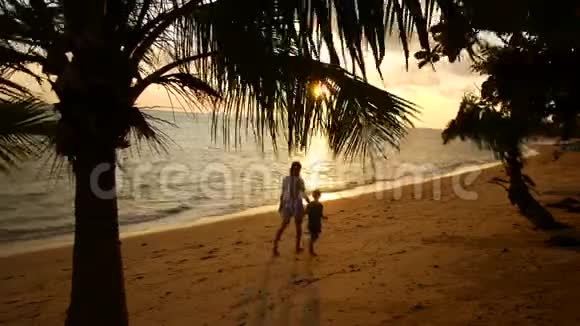 母亲和女儿在日落时沿着海岸散步视频的预览图