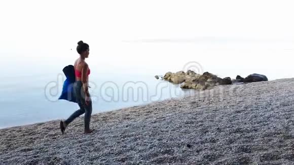 年轻健康的女人在鹅卵石滩上瑜伽课视频的预览图
