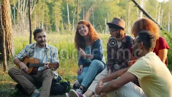 夏天男人和女人在森林里弹吉他和唱歌视频的预览图