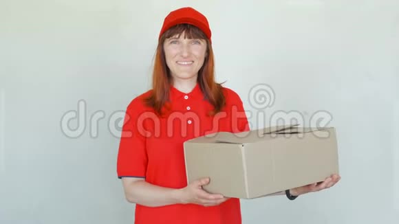 送微笑的女人穿红色制服戴帽子穿t恤穿牛仔裤的女性做快递或拿纸板的经销商视频的预览图
