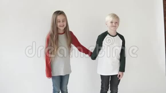 男孩和女孩牵手孩子们站在白色背景的画室里视频的预览图
