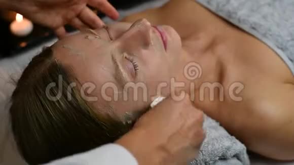 美容师正在去除女性脸上的黏土面具女性在水疗中心接受美容治疗视频的预览图
