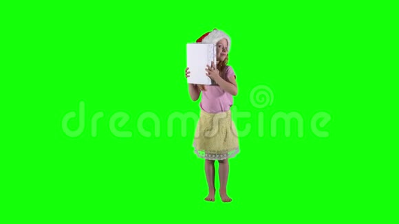 好奇的红发女孩带着礼品盒和圣诞帽Chroma关键背景视频的预览图