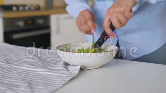 女人在碗里切牛油果做健康的素食早餐视频的预览图