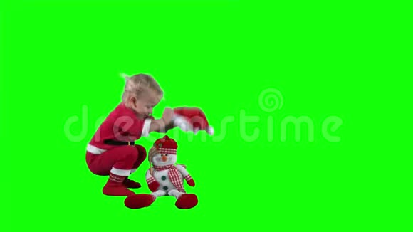 可爱的小圣诞老人小孩把圣诞老人的帽子戴在玩具雪人的头上视频的预览图