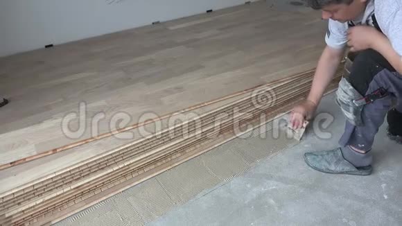 汉德曼在混凝土地板上涂胶粘剂工人安装木地板视频的预览图