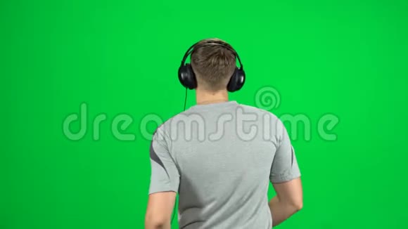 戴着大耳机的人去录音室听音乐在绿色屏幕上跳舞背面视频的预览图