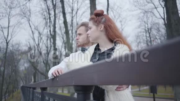 一对迷人的白种人夫妇站在桥边聊天秋天公园的时尚男女约会视频的预览图