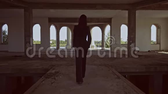 从后景中黑发女人走进被遗弃的建筑视频的预览图