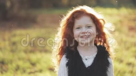 可爱的红头发小女孩在秋天公园散步的肖像慢动作秋天公园小女孩微笑着视频的预览图
