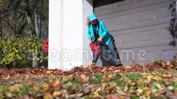 女工人从车库入口吹树叶女孩用吹叶机视频的预览图